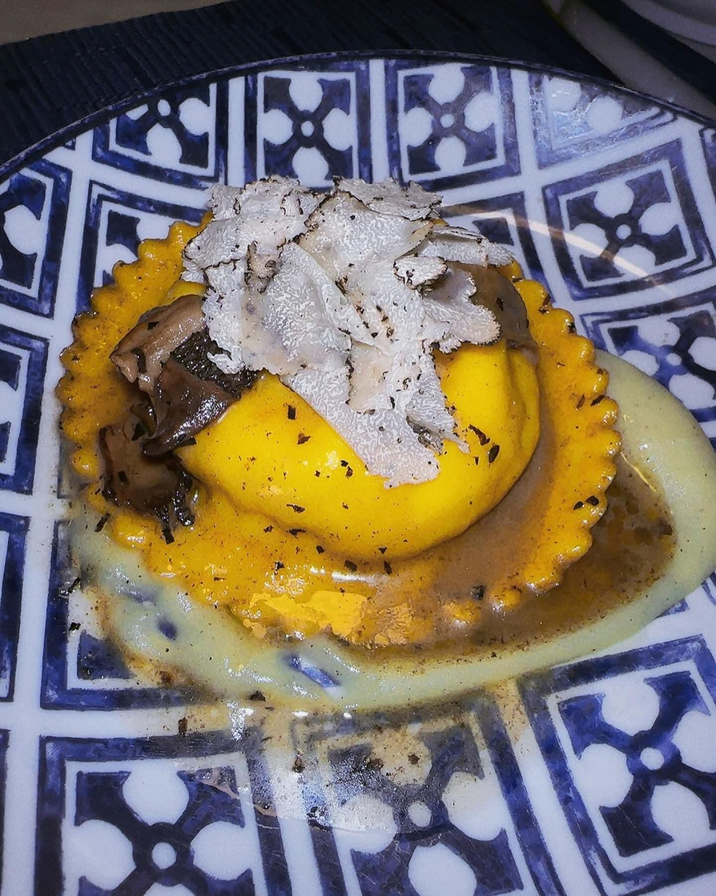 A meticulously crafted ravioli topped with shaved truffles on a beautifully patterned plate, representing the luxurious dining options that Booked offers in the heart of New York City's restaurant scene.
