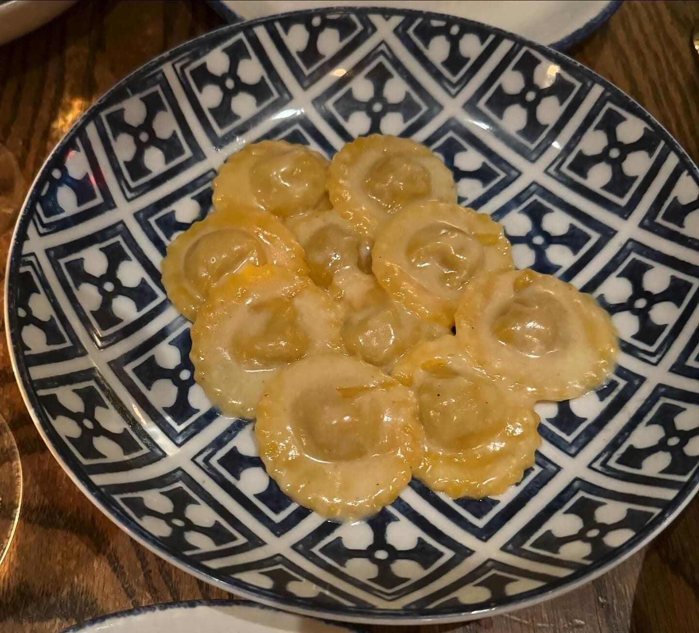 Delicate stuffed pasta served on an ornate blue and white patterned plate, showcasing the art of Italian cuisine available for booking at New York's finest eateries through Booked.